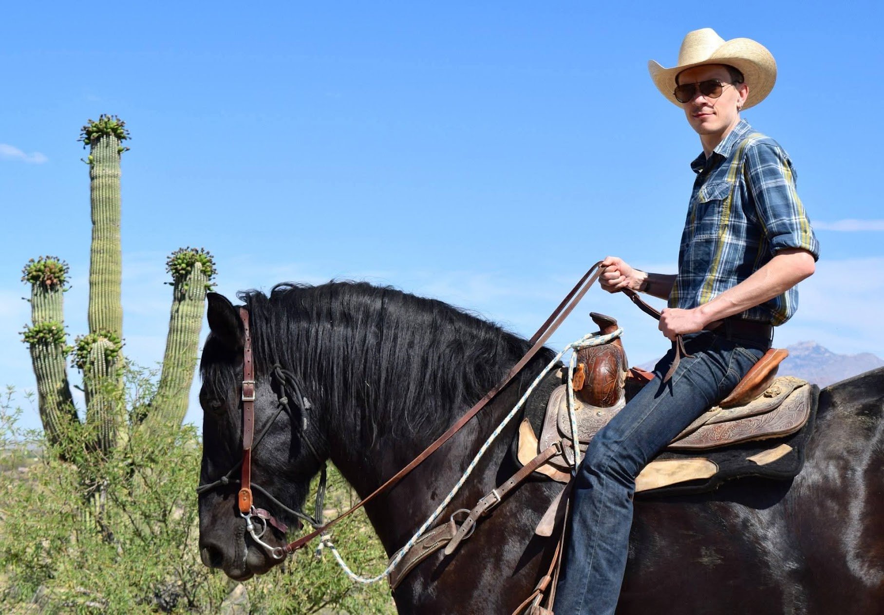 Saxon Burns on horseback in the Arizona desert among saguaro cacti.