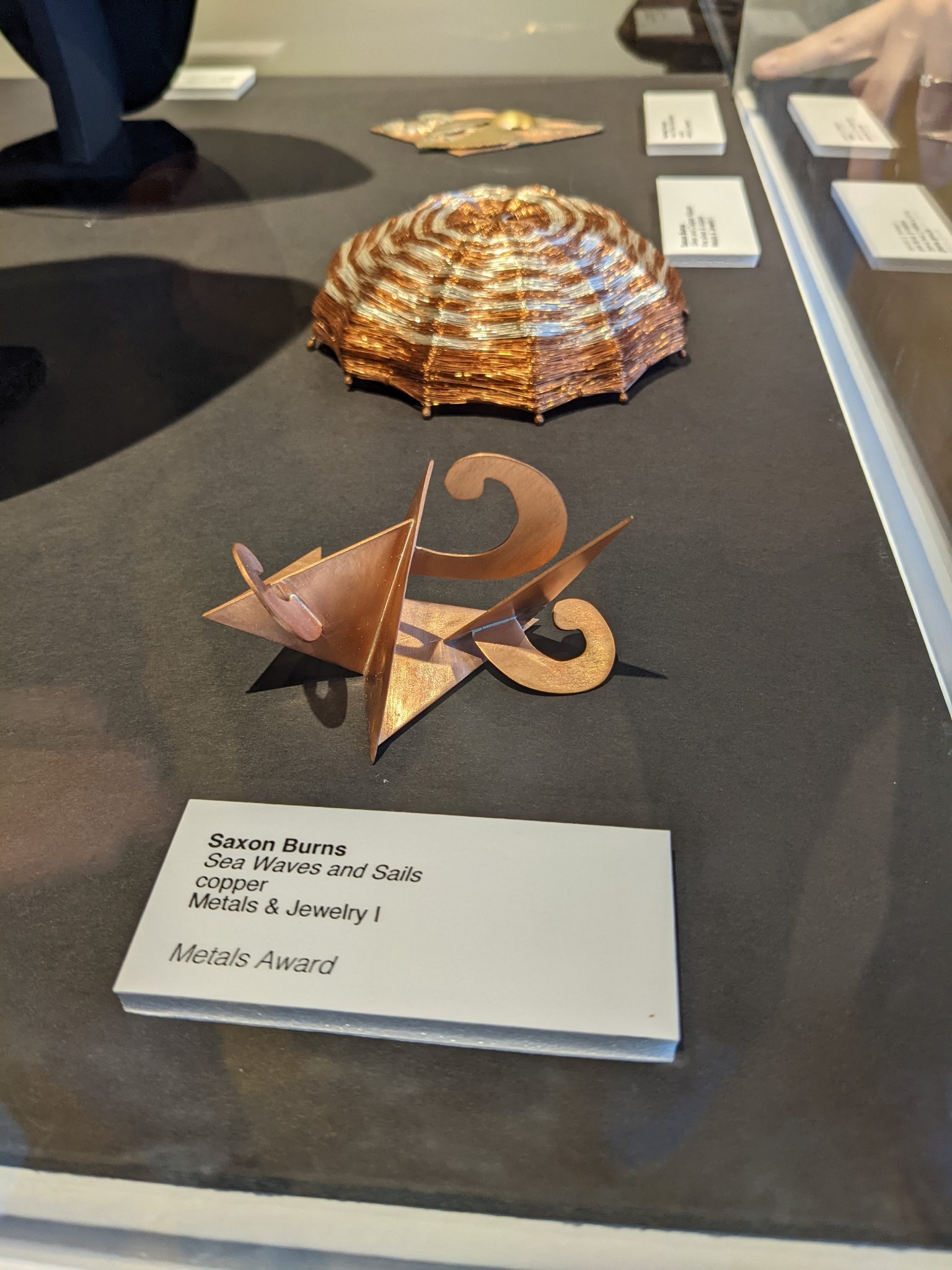 Sea Waves and Sails copper piece displayed beside its award label.